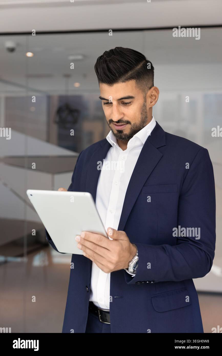 Handsome Indian businessman working on digital tablet in workspace Stock Photo
