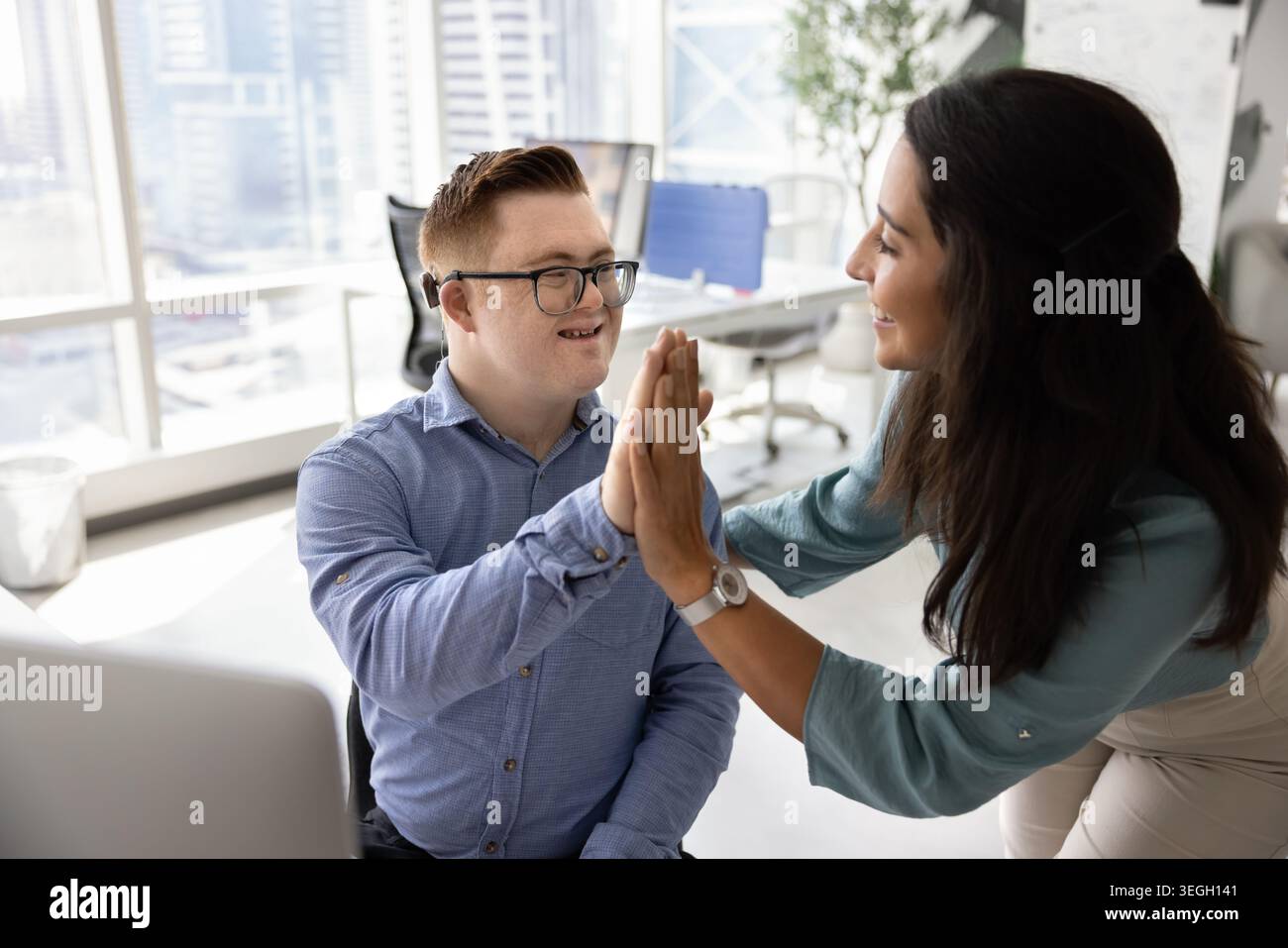 Woman giving high five to male colleague with Down syndrome Stock Photo
