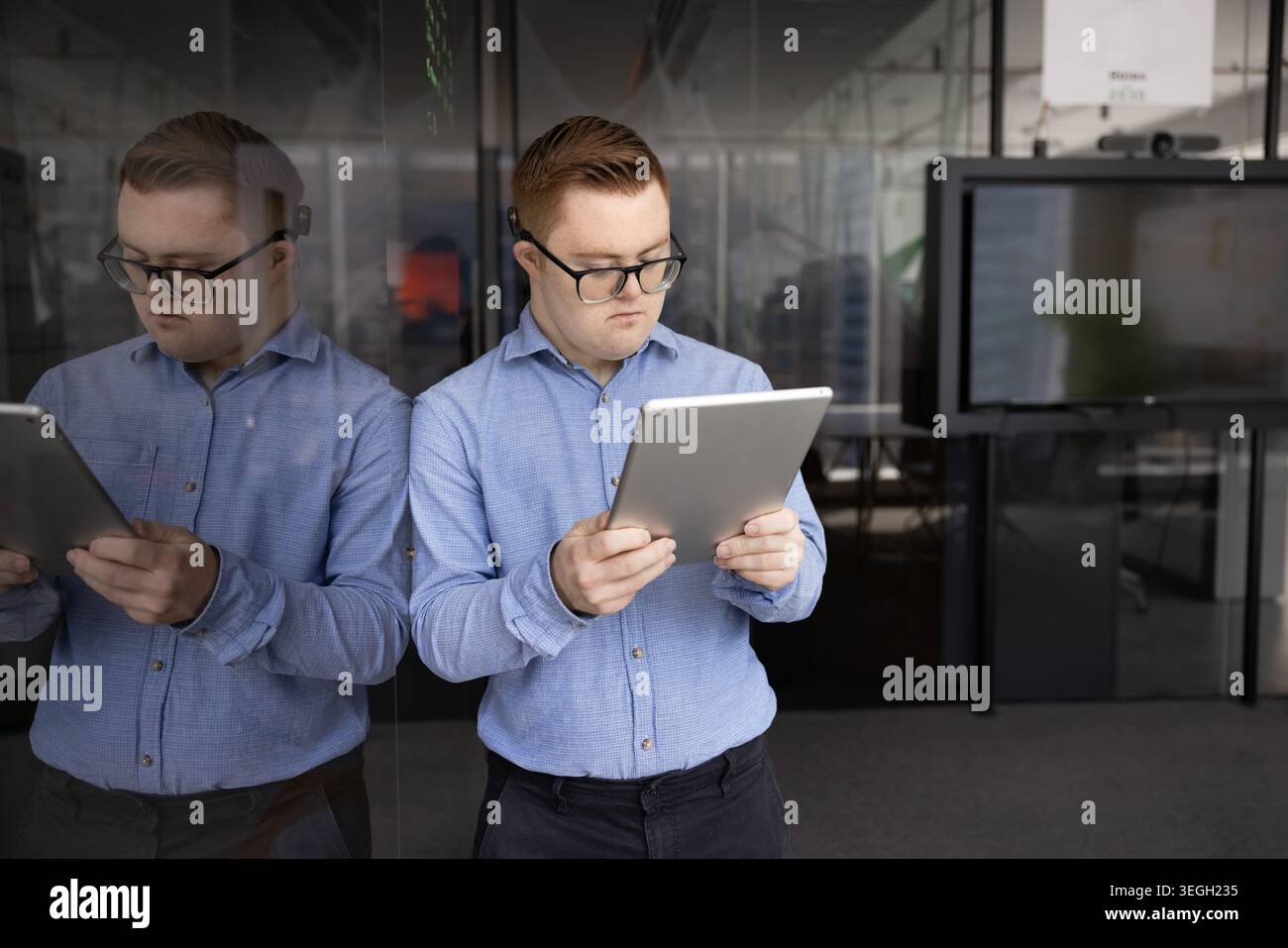 Young professional man with Down syndrome using tablet in office Stock Photo