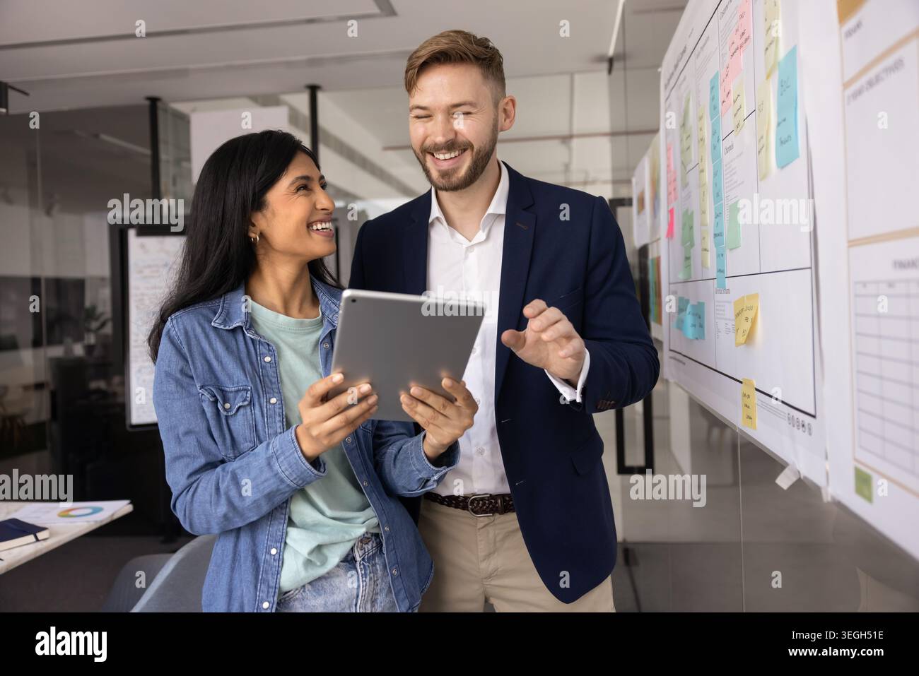 Teammates laughing, enjoy collaborative discussion using tablet Stock Photo