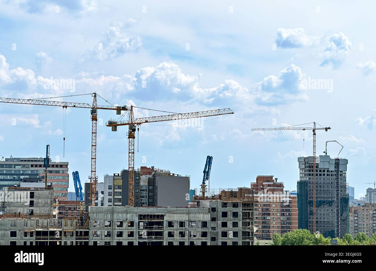 Urban Development: Tower Cranes Constructing Modern High-Rise Buildings Against Cloudy Skyline Stock Photo