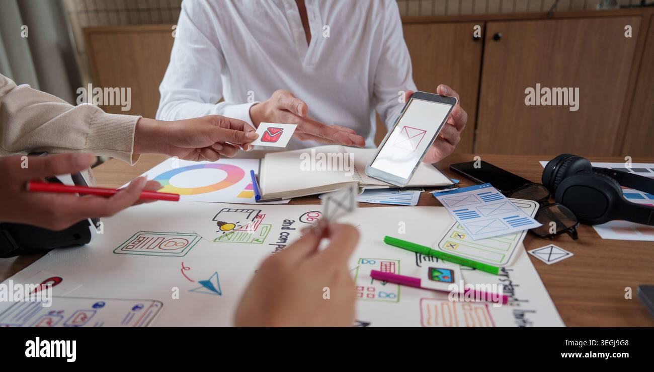 Asian UX UI designers collaborating on mobile application interface development in office. Stock Photo
