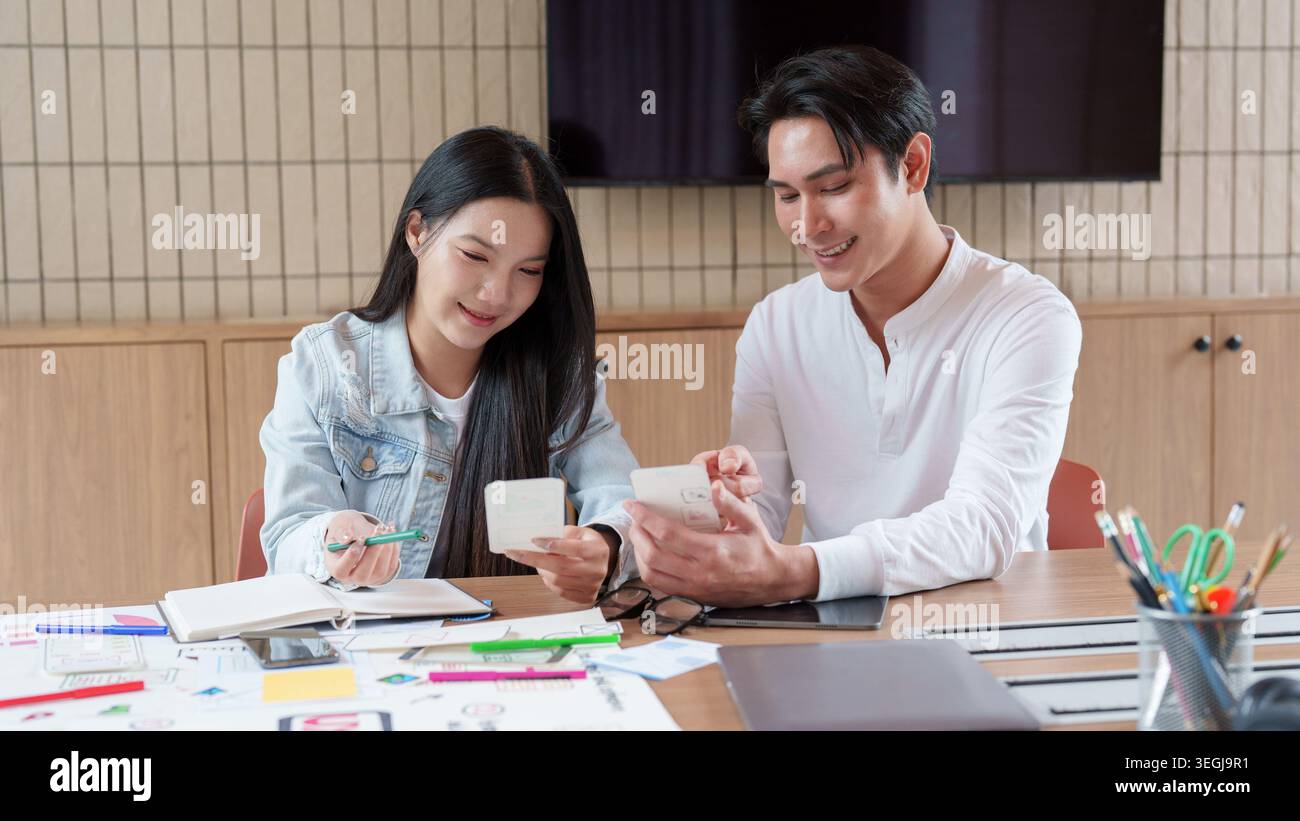 Asian UX UI design team collaborating on mobile app interface in office Stock Photo