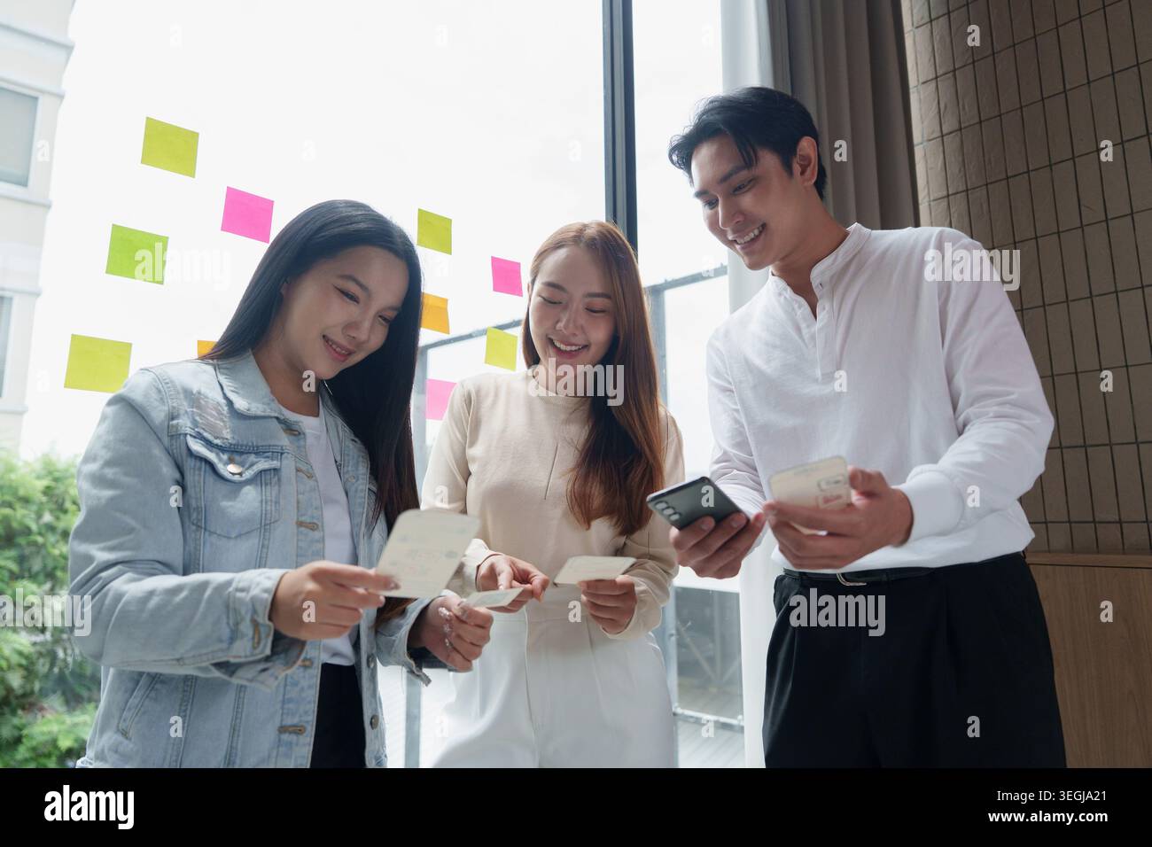 Asian UX UI designers collaborating on mobile application development in office. Stock Photo