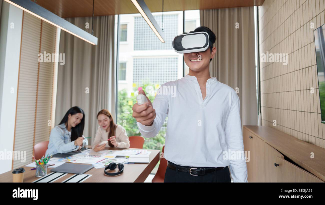Asian man using virtual reality headset with controller in modern office. Stock Photo