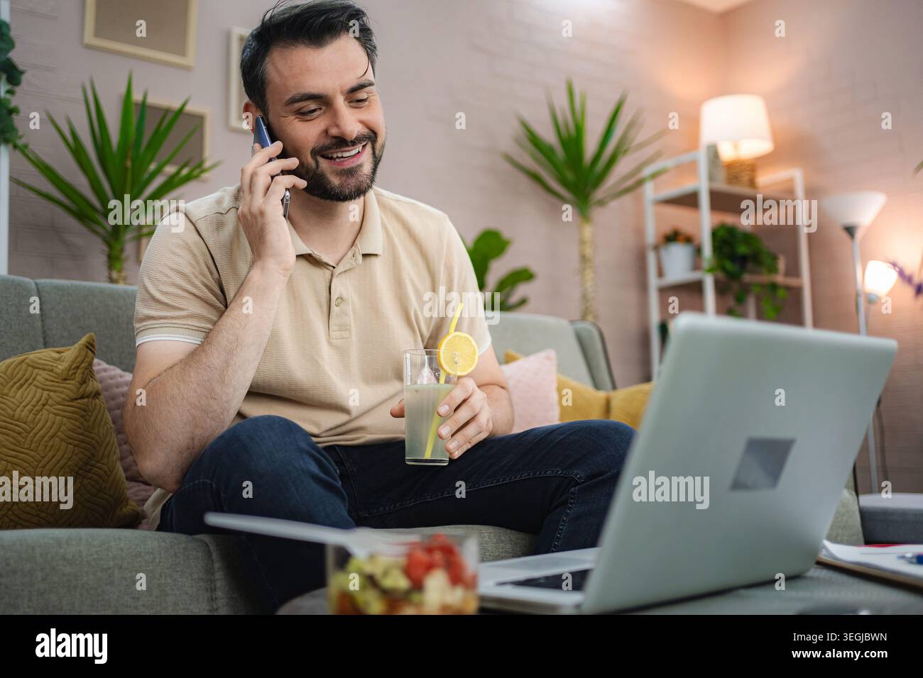 Freelancer enjoying a refreshing drink while working from home Stock Photo