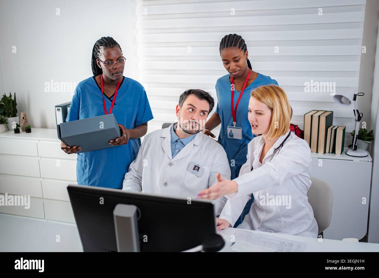 Medical team collaborating and discussing patient data on computer Stock Photo