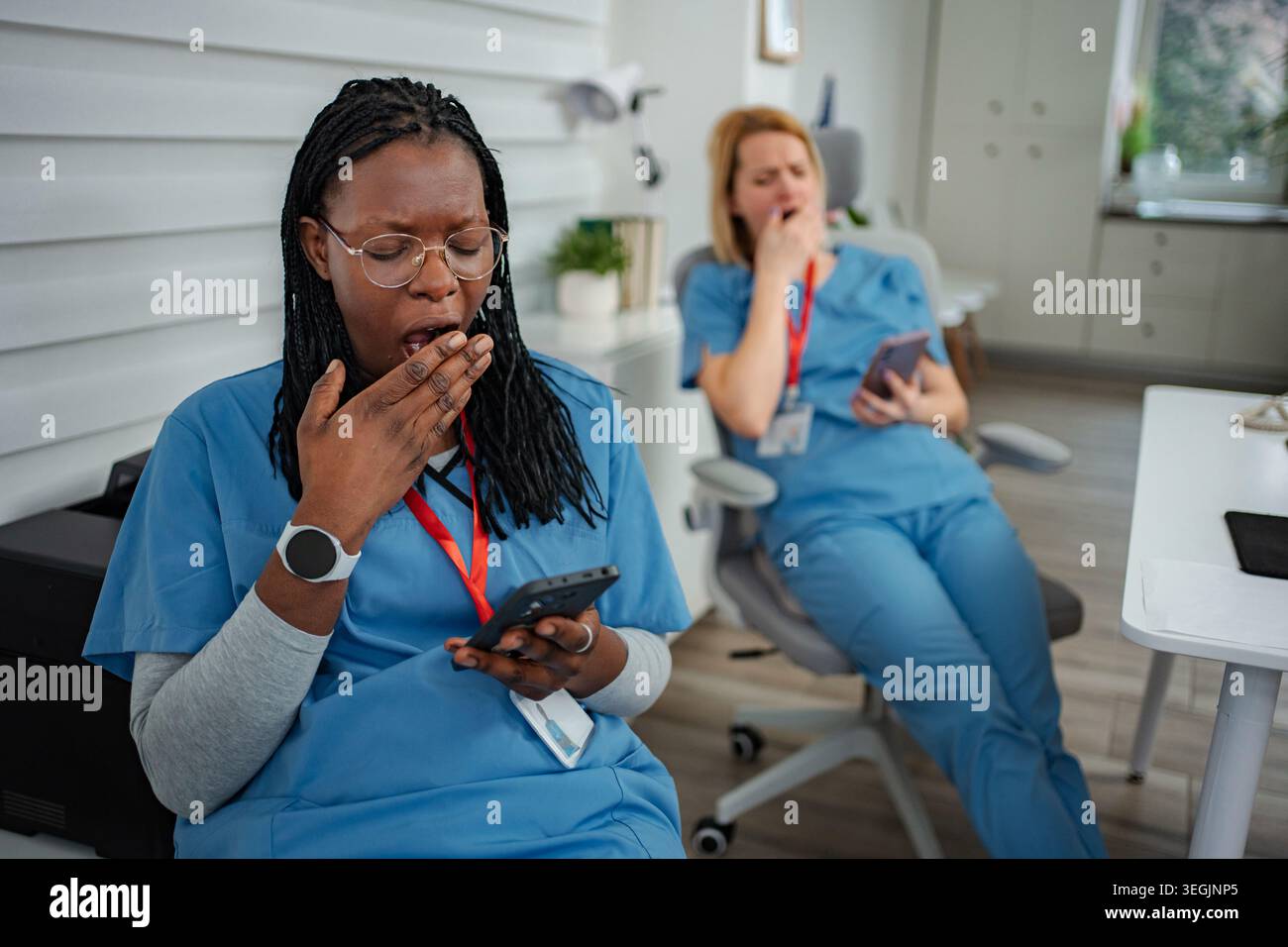 Tired medical workers yawning during long shift break Stock Photo