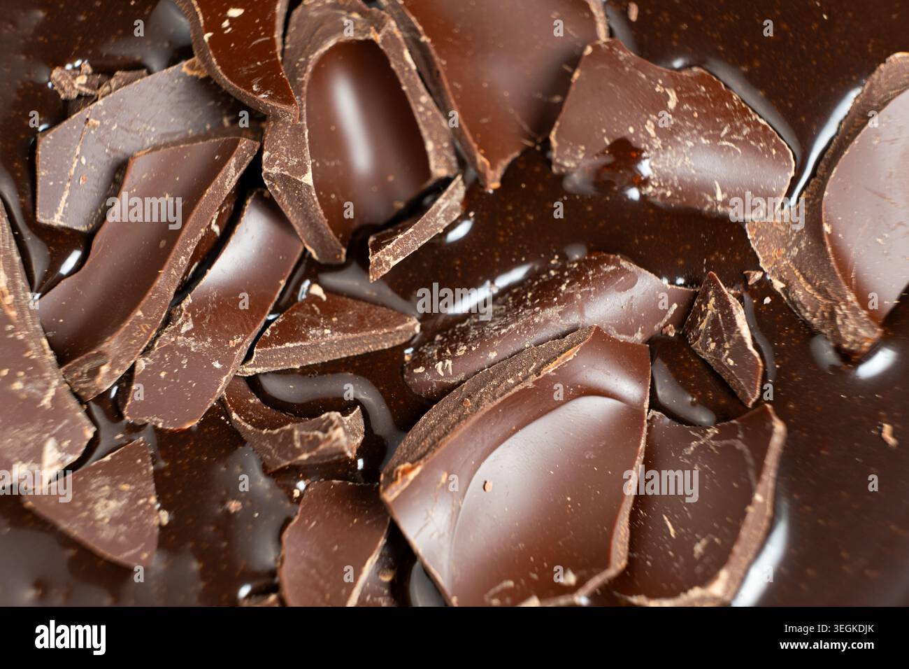 Dark chocolate chunks into liquid melted chocolate sauce background Stock Photo