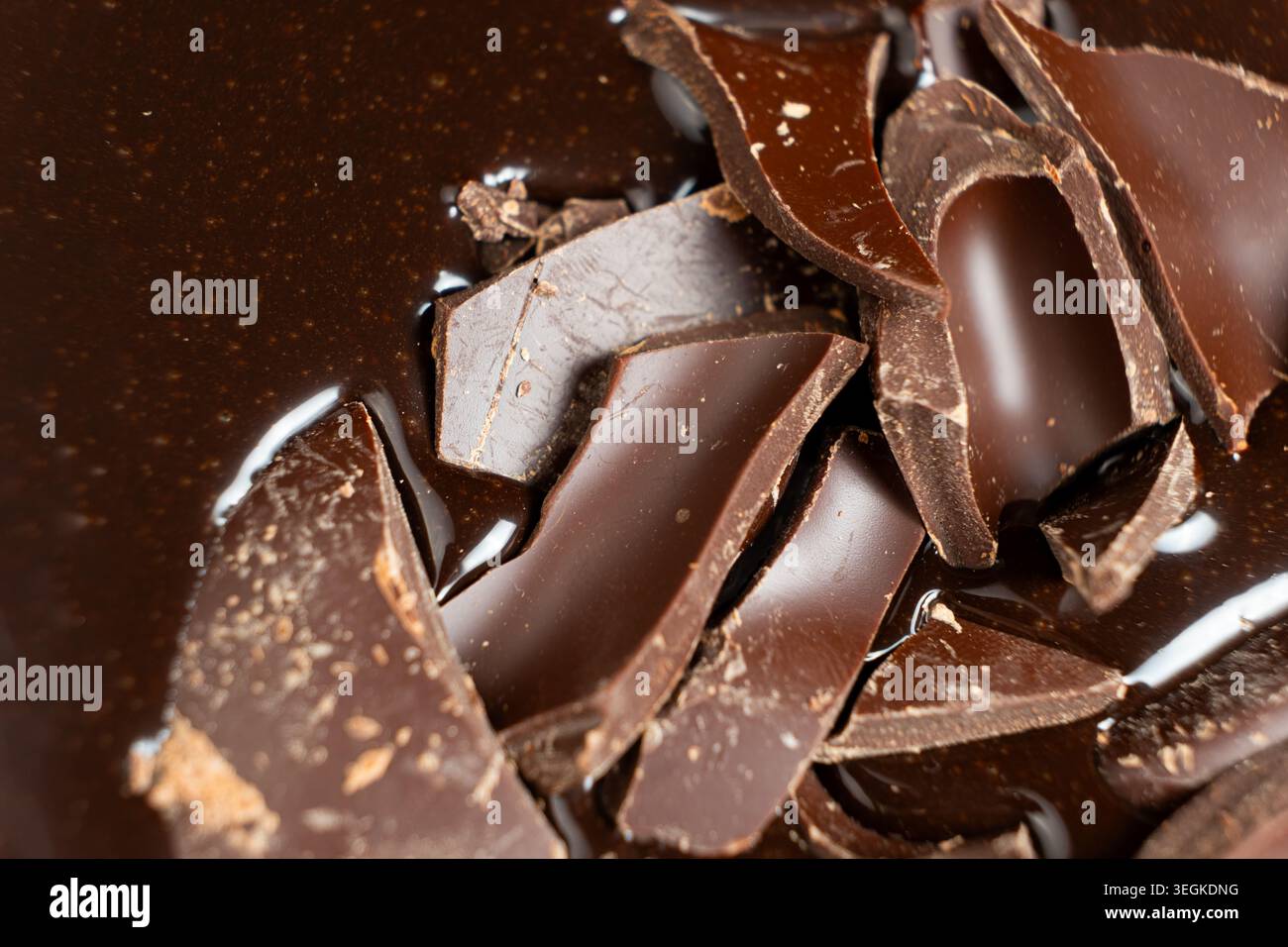 Dark chocolate chunks into liquid melted chocolate sauce background Stock Photo