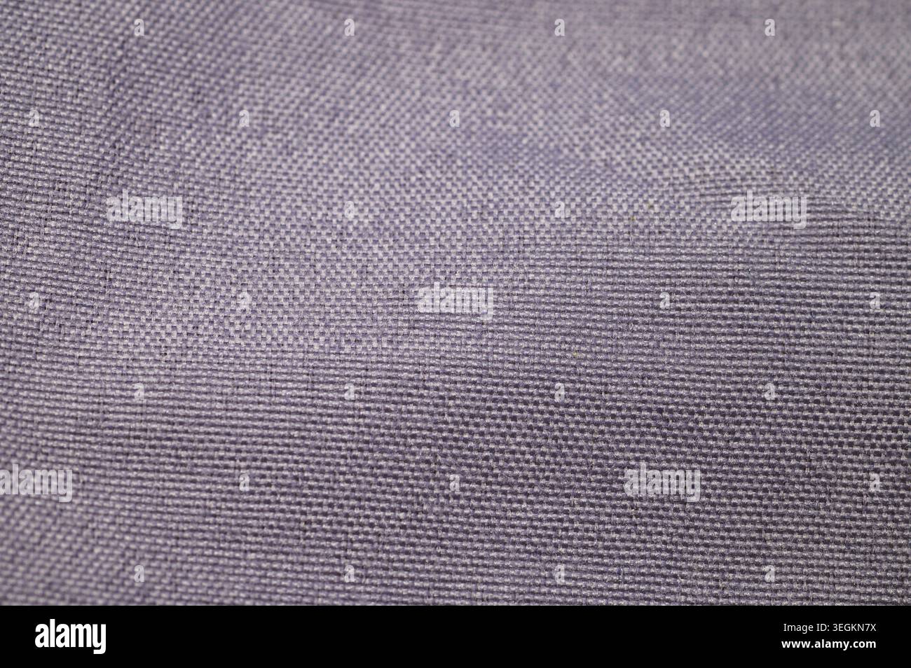 Close-up texture of a woven fabric with a subtle purple hue and visible threads Stock Photo