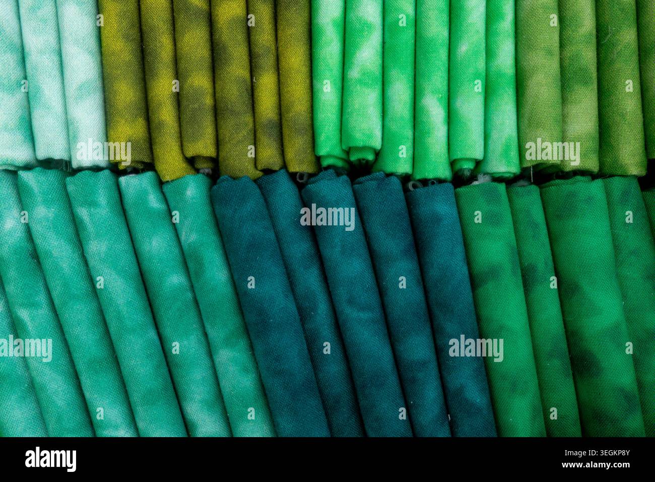 Fabric swatches arranged in rows displaying a gradient of colors from light to dark green, highlighting a textile collection with diverse patterns and Stock Photo