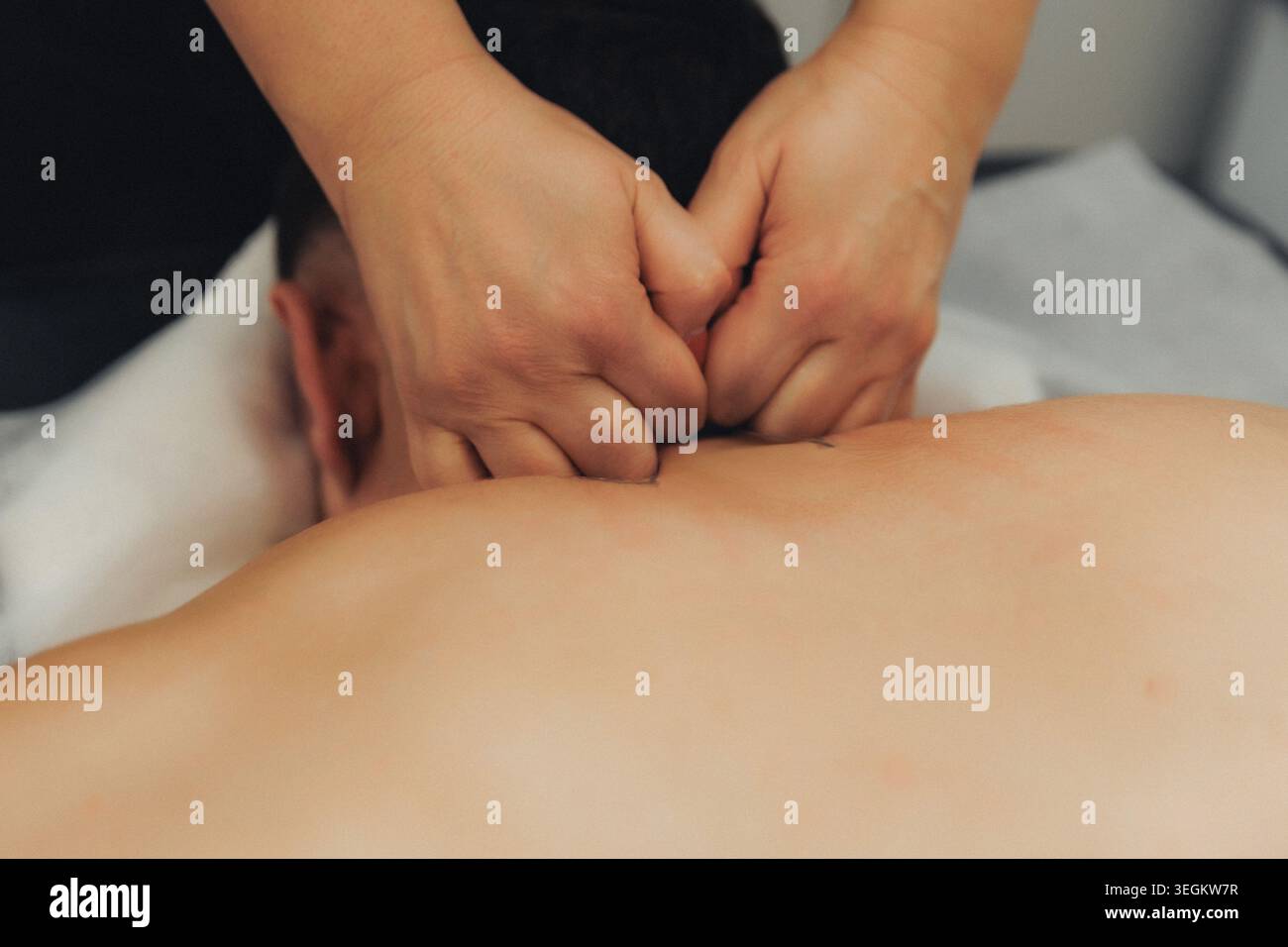 Two hands gently press into a person's spine Stock Photo