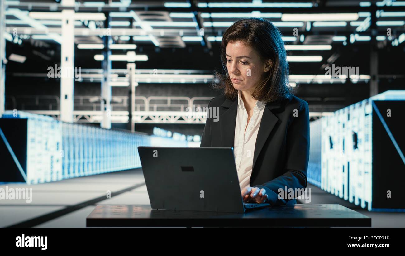 Data center engineer typing on laptop keyboard to troubleshoot supercomputers connectivity issues. Server hub expert using program on notebook to analyze system logs, fixing gear errors Stock Photo