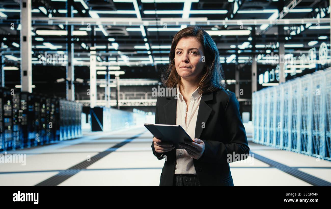 Smiling data center DevOps technician optimizing server load balancing using tablet app. Happy server hub employee worker adjusting system parameters on device to improve efficiency Stock Photo