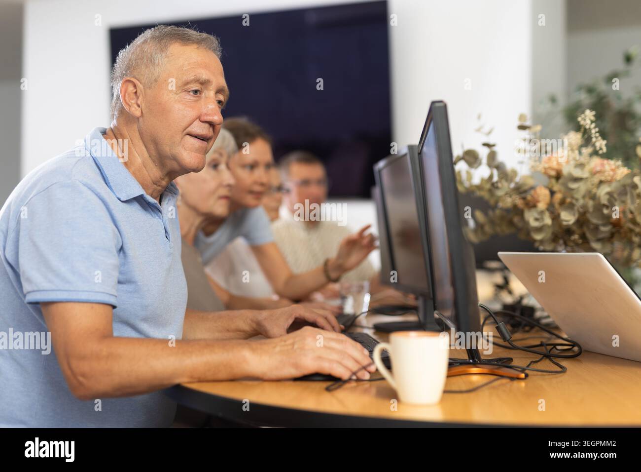 Enthusiastic senior man attending computer class for older adults Stock Photo