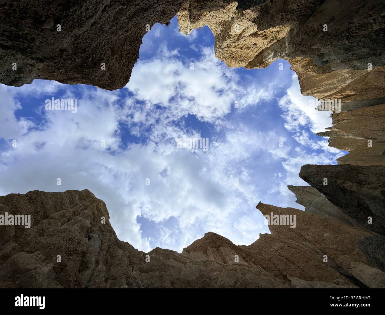 Looking Up Through Jagged Clay Cliffs Canyon Opening to Blue Sky and Clouds in New Zealand Stock Photo