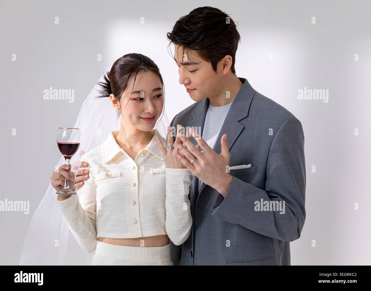 A young couple, newly married, share a toast with wine and exchange rings in a romantic, candle-lit setting. Stock Photo