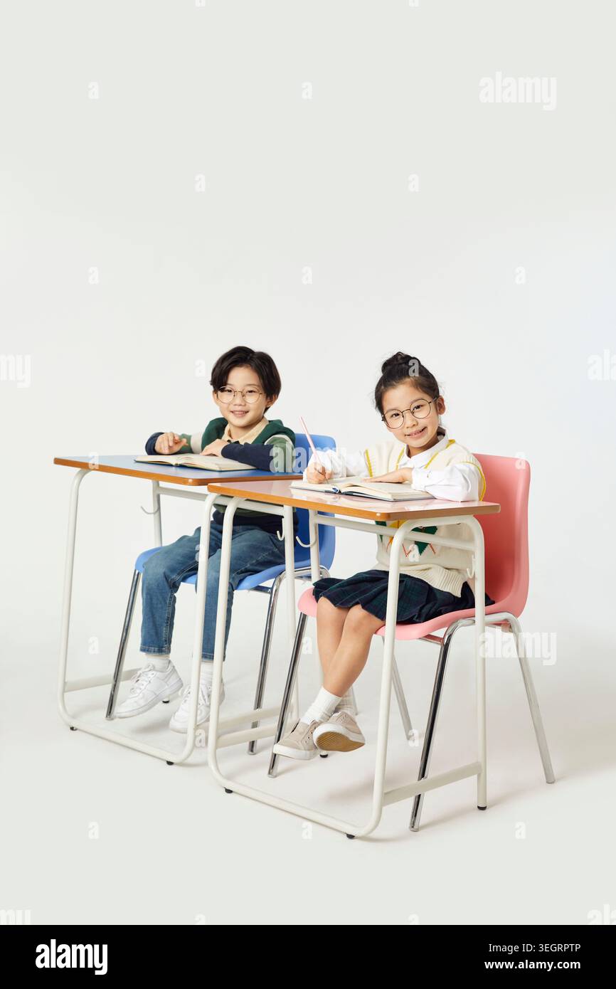 Two students in a classroom, smiling at the camera while studying together. Stock Photo