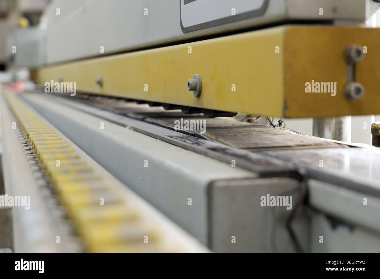 Industrial machine operating with a yellow conveyor belt showing parts ...