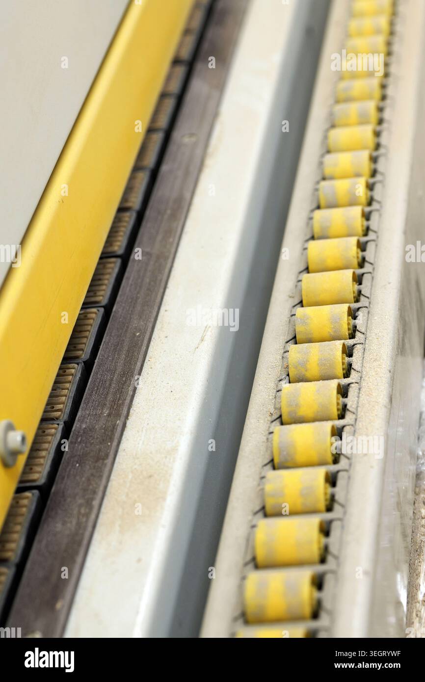 Industrial equipment detail showing dirty yellow rollers on a conveyor ...