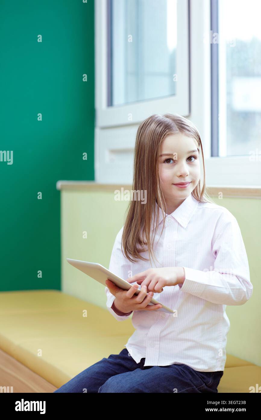 a girl using tablet PC while sitting Stock Photo