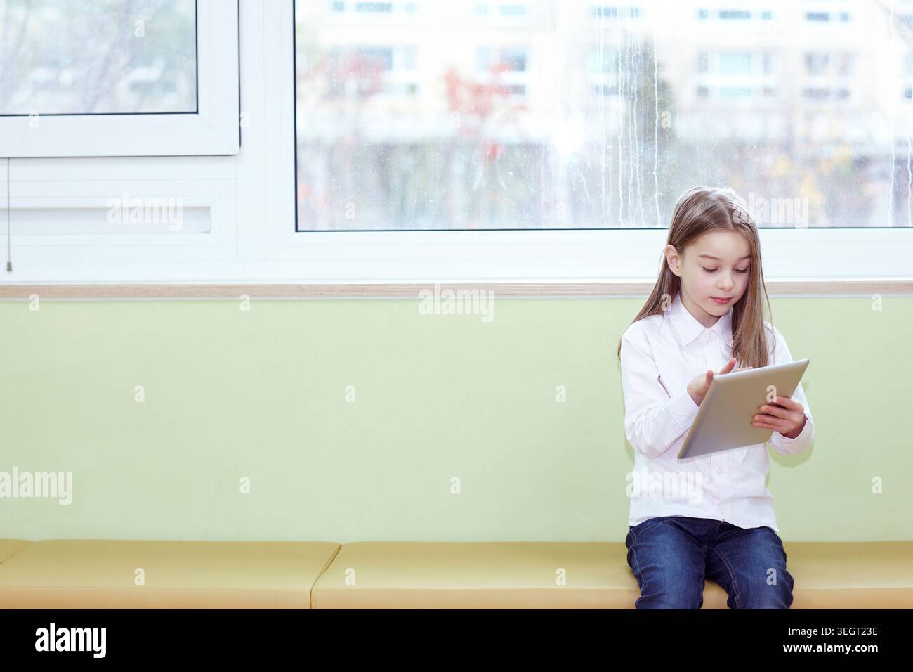 a girl using tablet PC while sitting Stock Photo