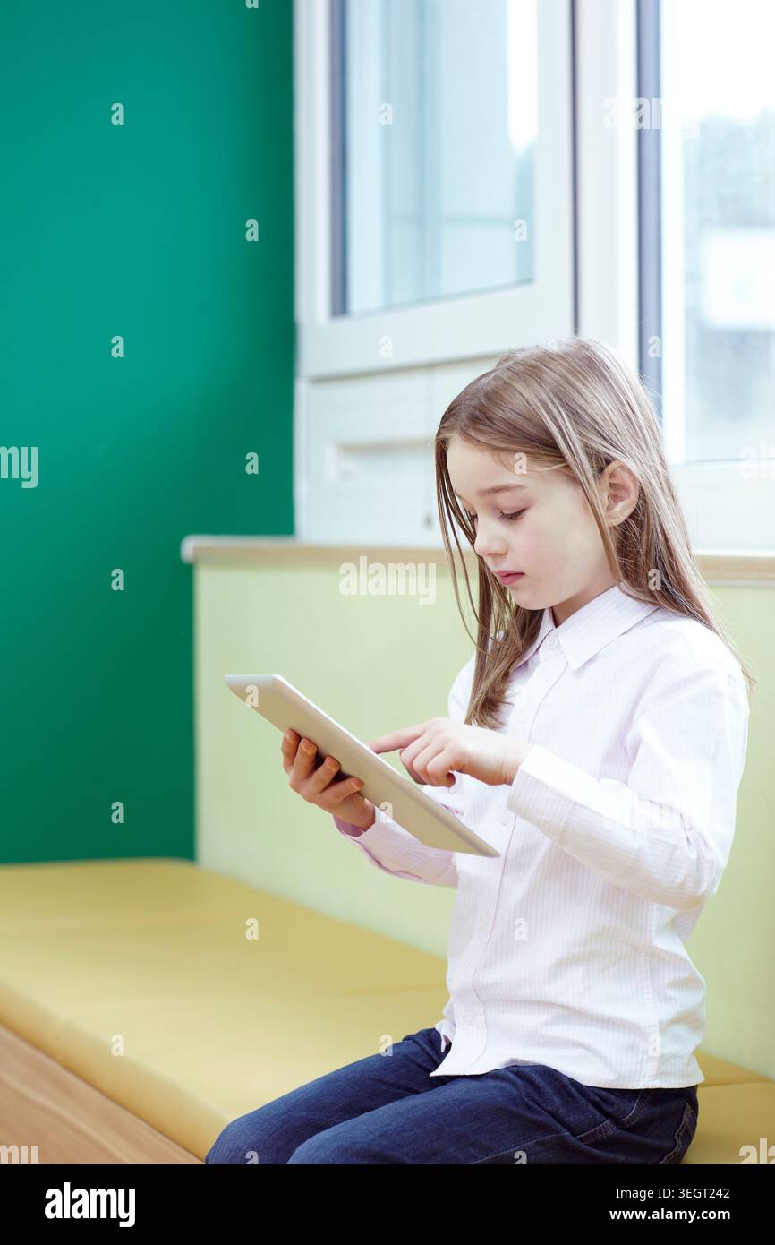 a girl using tablet PC while sitting Stock Photo