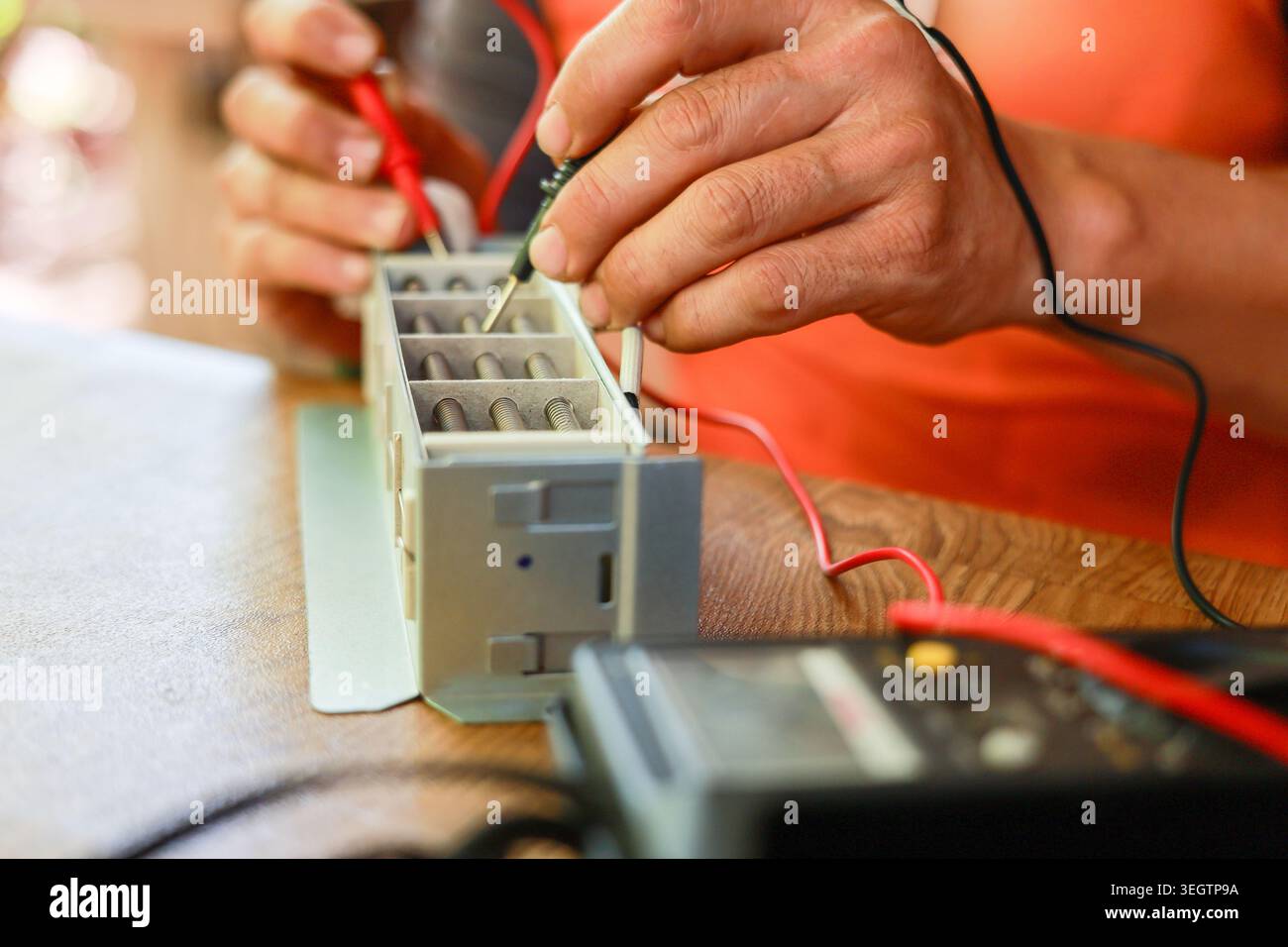Electrician hands demonstrate intense focus testing electronic component using multimeter during precise repair and maintenance work on industrial equ Stock Photo