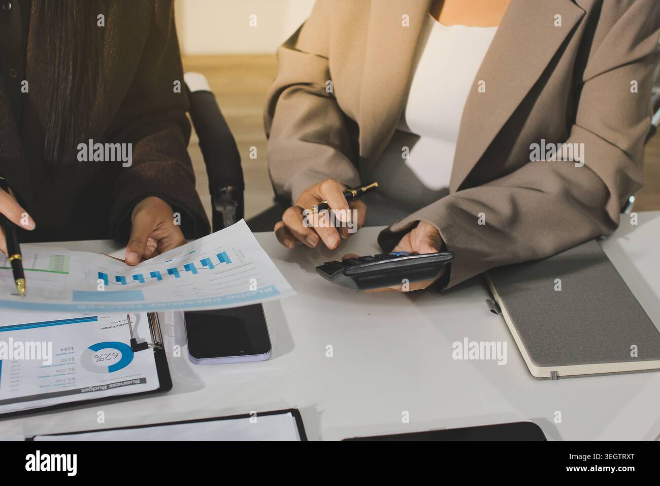 Two young Asian businesswomen discuss investment project working and ...