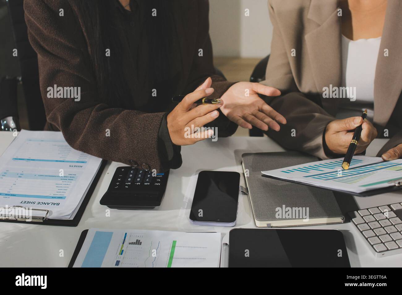 Two young Asian businesswomen discuss investment project working and ...