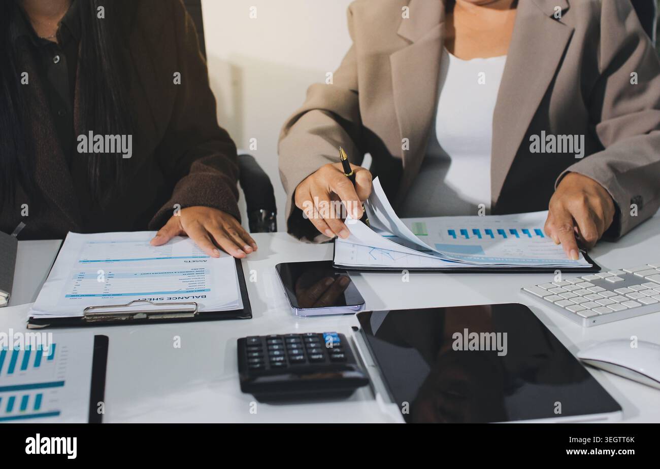 Two young Asian businesswomen discuss investment project working and ...