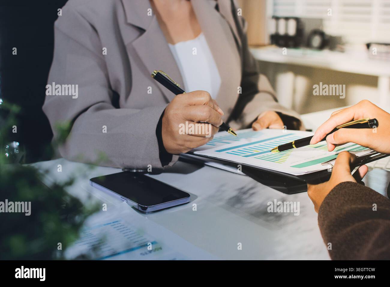 Two young Asian businesswomen discuss investment project working and ...