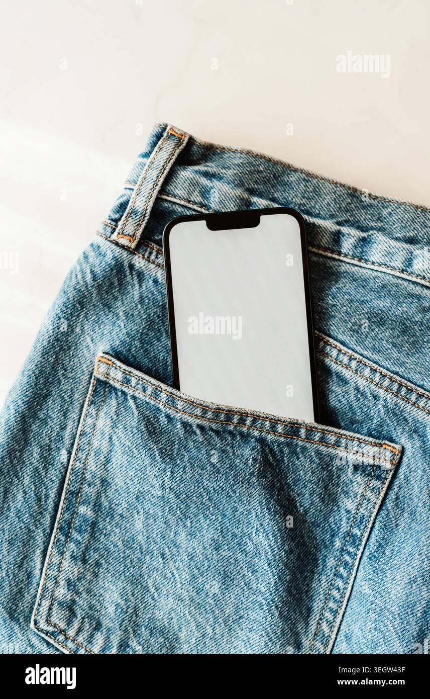 Smartphone with blank screen in a blue denim jeans pocket, casual fashion and technology concept with copy space for app or mobile design. top view Stock Photo
