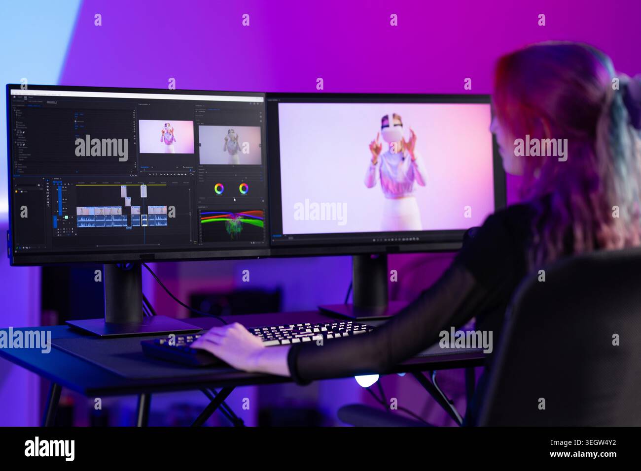 Young female video editor working on creative project with dual monitors Stock Photo