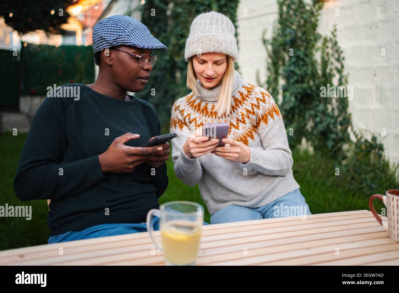 Two diverse friends connecting using smartphones outdoors Stock Photo