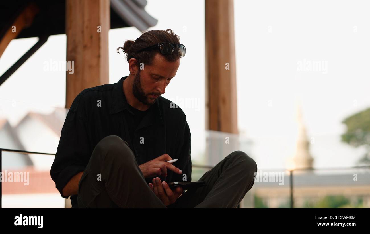 Man working remotely outdoors using tablet and stylus for creative design Stock Photo