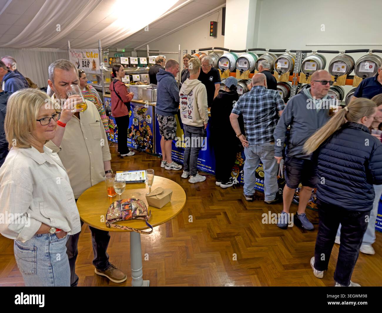 Crowded indoor real ale festival at Grappenhall GYCA Bellhouse, Warrington, showing beer pumps, drinkers and community event atmosphere. Stock Photo