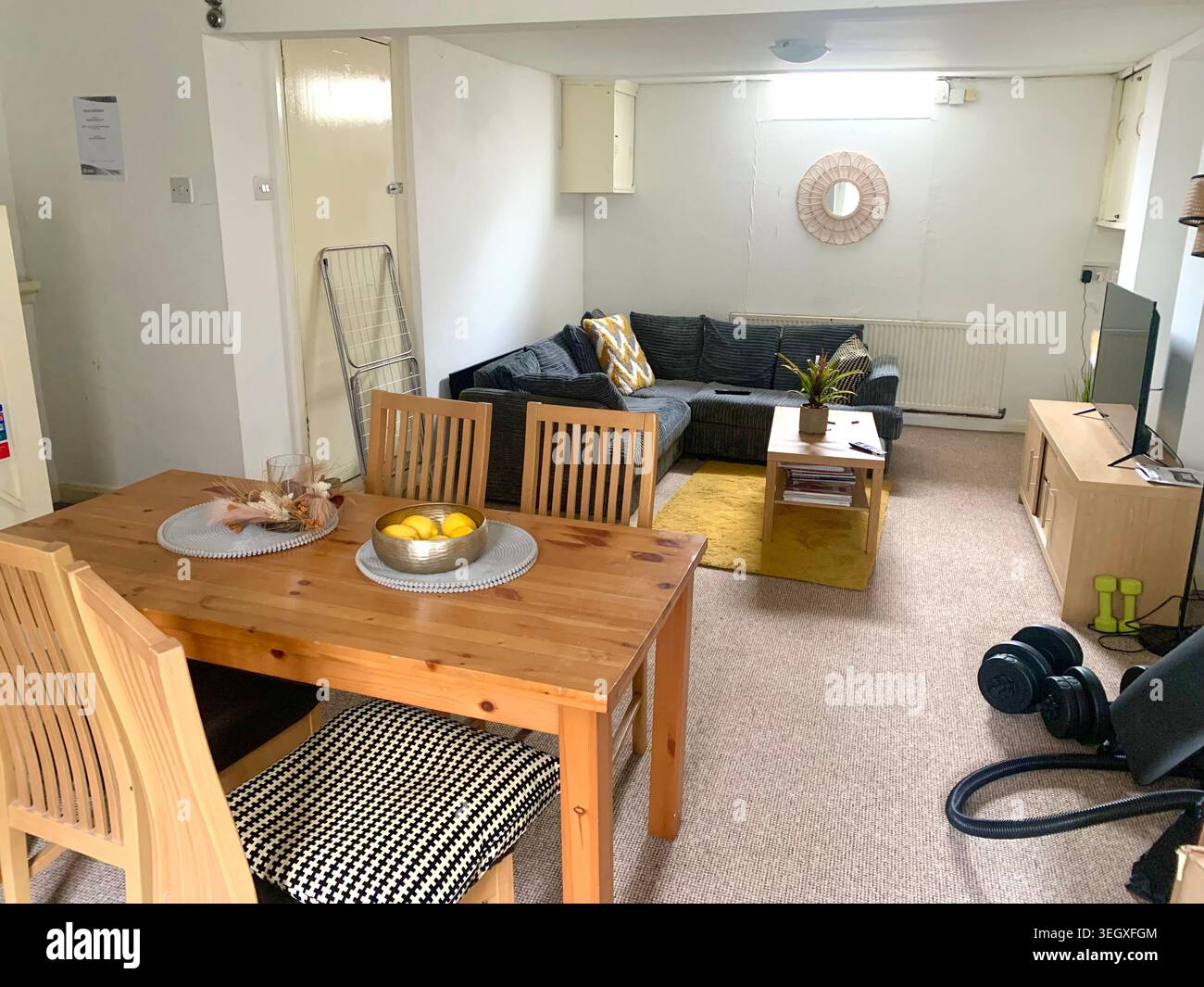 cozy modern living space with wooden dining table and comfortable sofa blending dining and relaxation in a bright compact home in England UK British - Smartphone Captured Stock Image