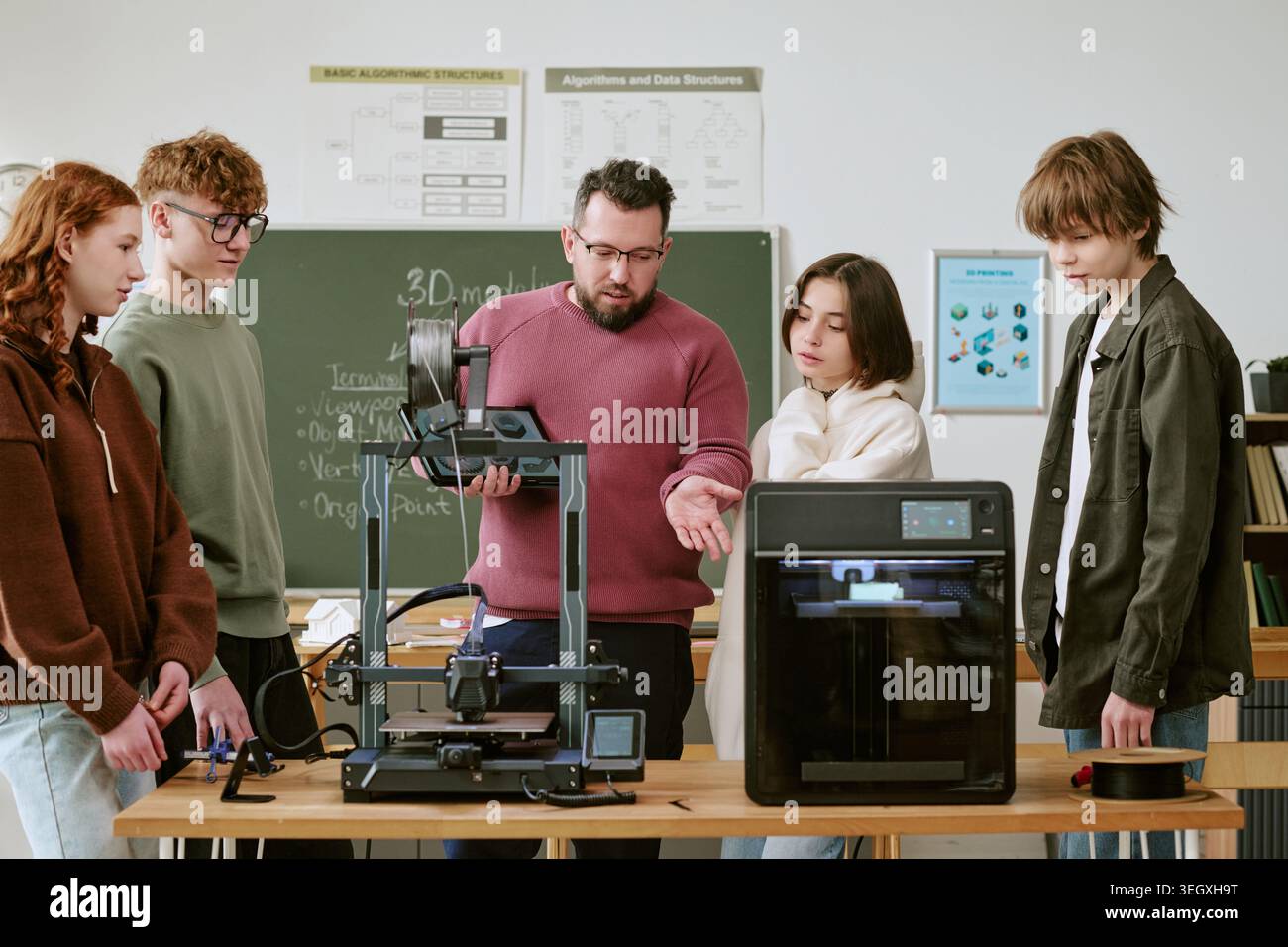 Teacher Guiding Teenagers Using 3d Printers in Stem Classroom Stock Photo