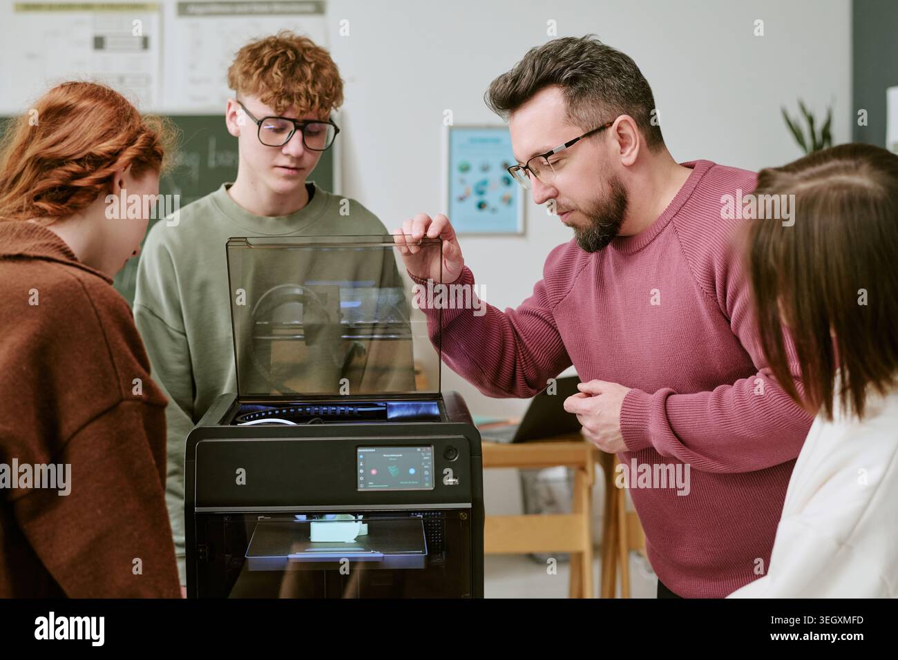 Teacher Guiding Teenagers Using 3d Printer in Classroom Stock Photo