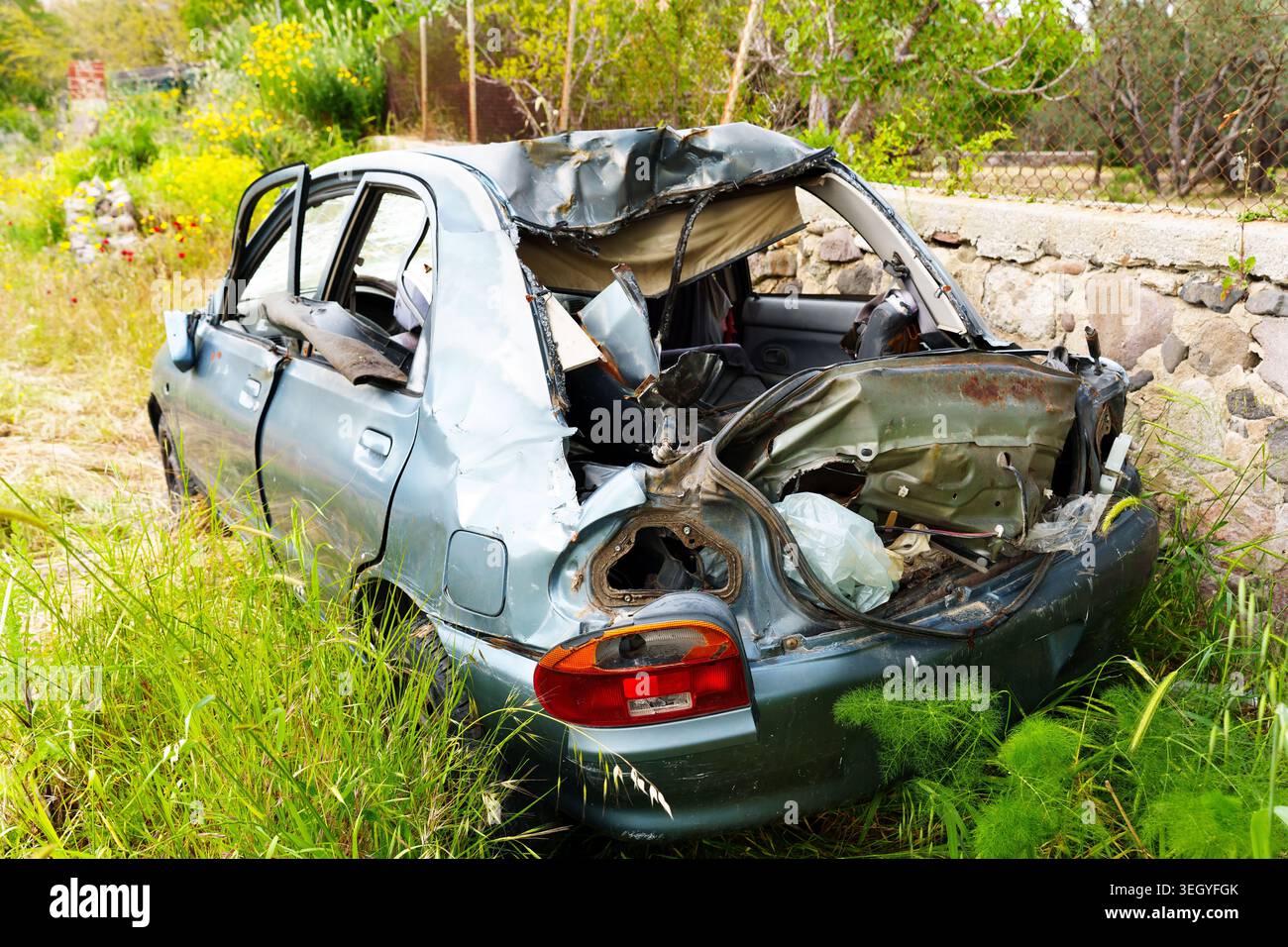 Abandoned car wreckage with crushed roof and smashed windows sits in ...