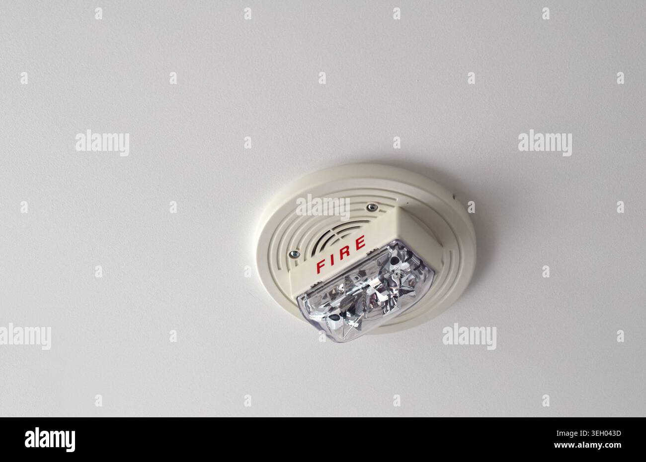 White fire alarm unit mounted on an apartment ceiling featuring speaker and strobe light, with visible “FIRE” marking as part of building safety syste Stock Photo