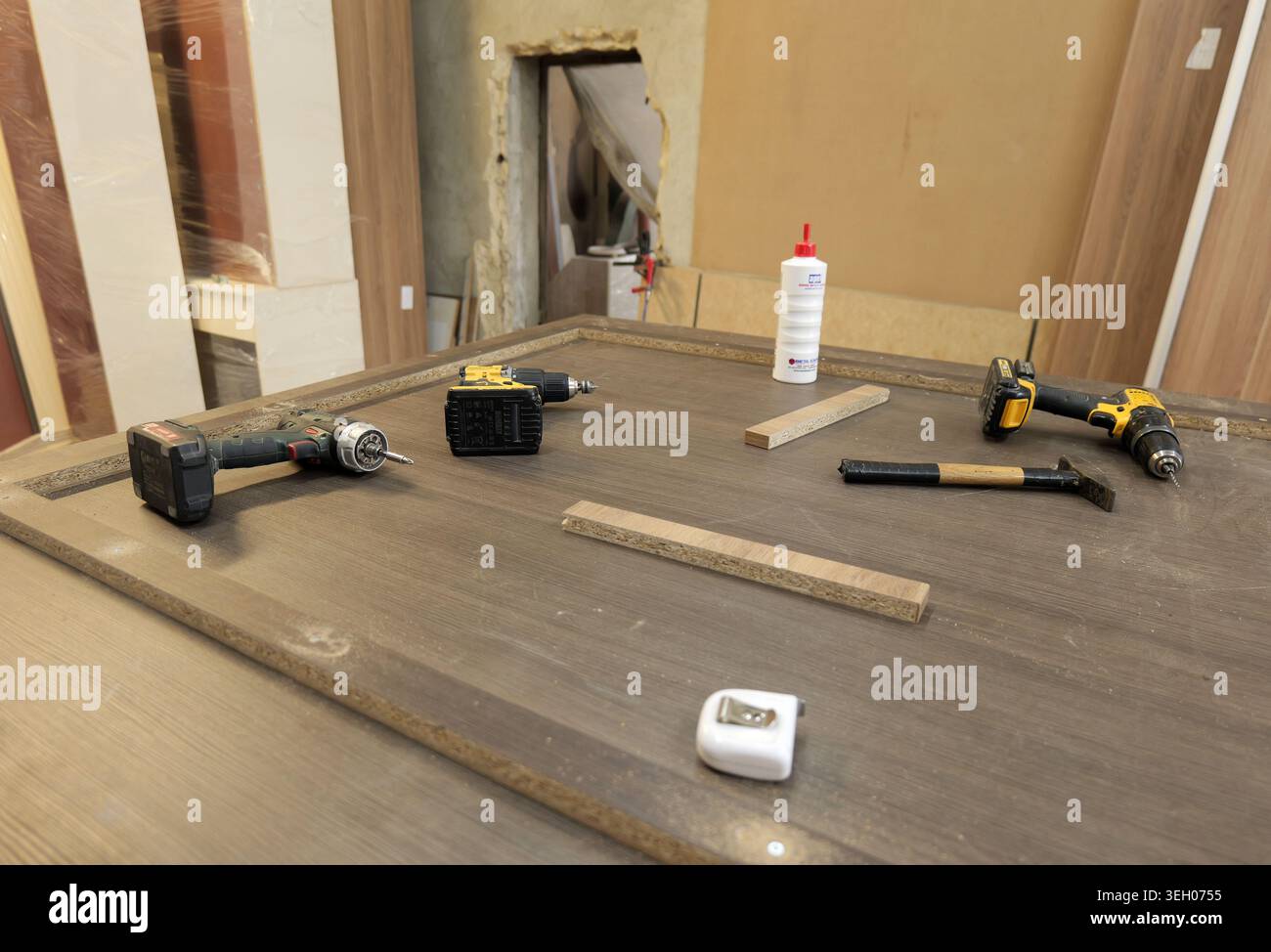 Drills, wood glue, and measuring tape are on a workshop workbench, depicting a scene of carpentry, assembly work, and furniture making using various h Stock Photo