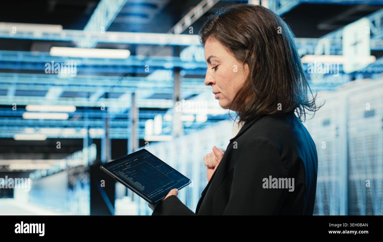 Data center programmer coding on tablet, optimizing equipment rigs using application. Close up of IT professional in server hub running programming script, adjusting system parameters Stock Photo