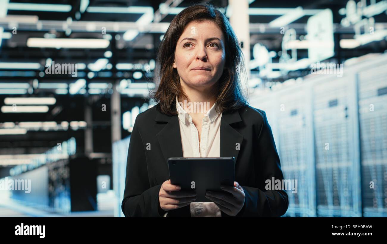 Smiling data center DevOps technician optimizing server load balancing using tablet app. Happy server hub employee worker adjusting system parameters on device to improve efficiency Stock Photo
