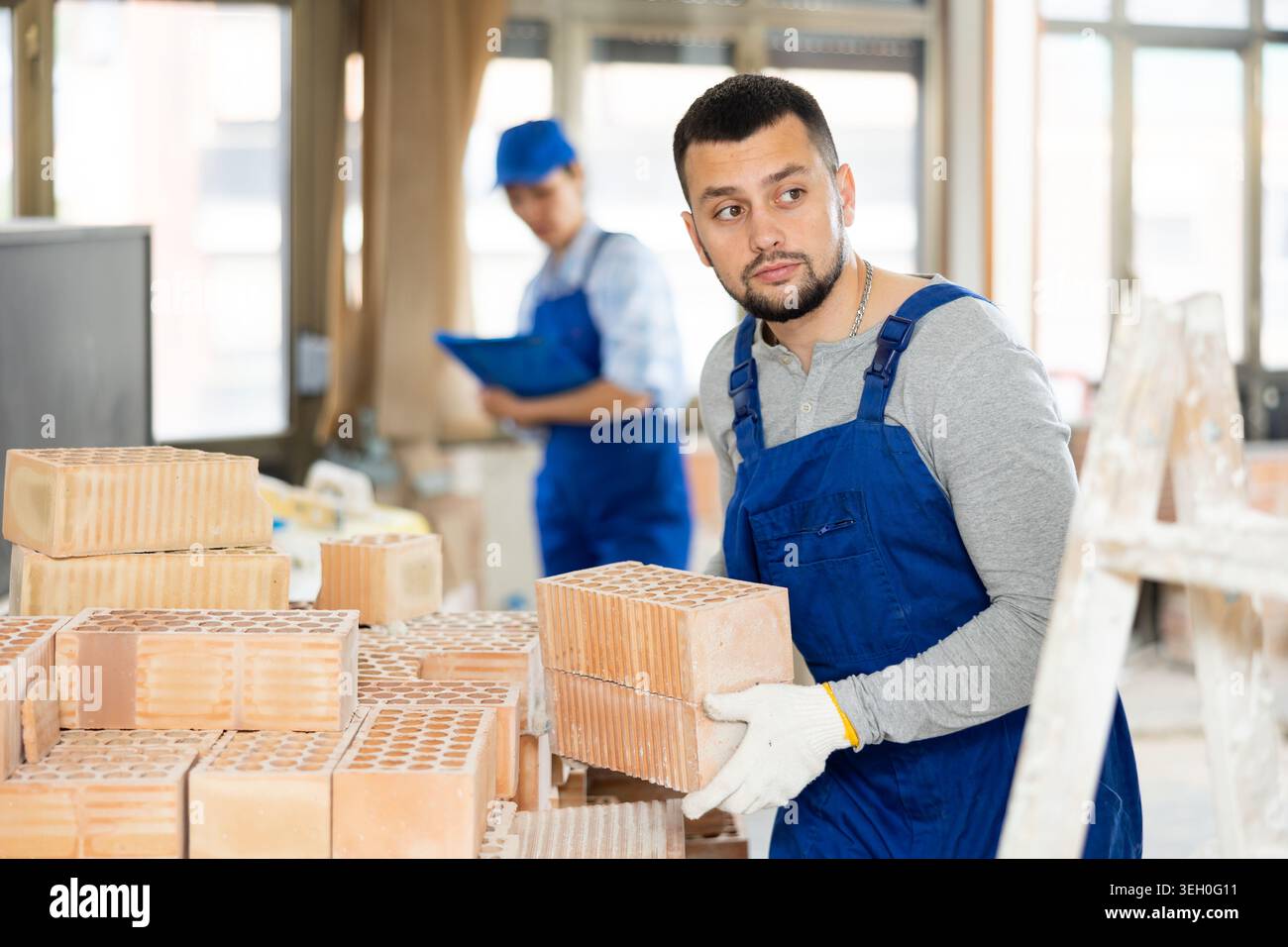 Repairman carrying bricks in construction site Stock Photo
