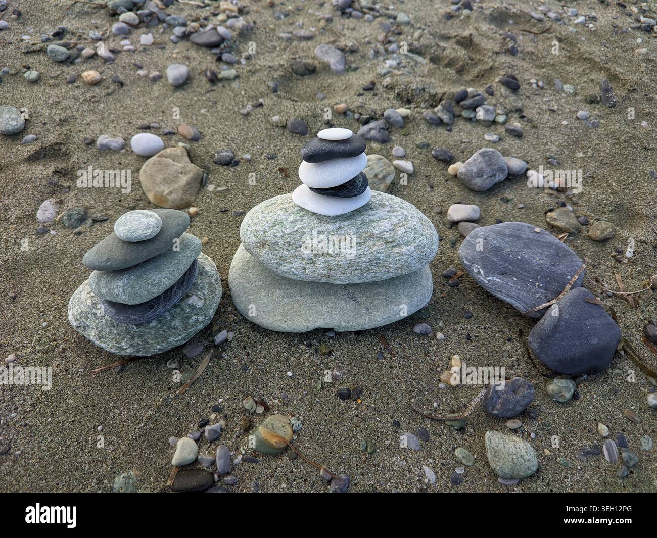 Zen stone pyramids and balanced pebbles on a sandy beach. Stock Photo