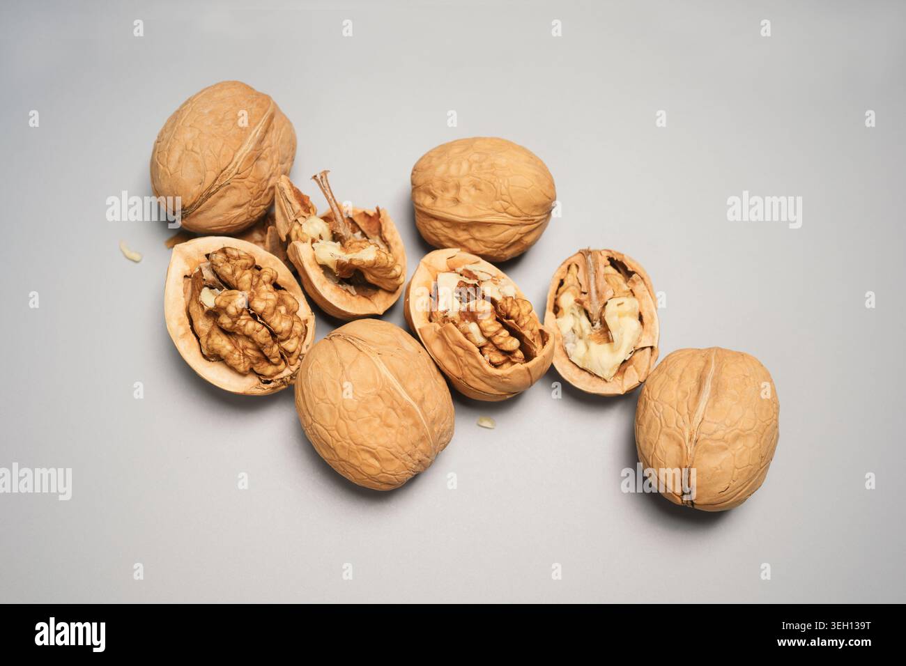 Walnuts in Shells and Cracked Open on a Gray Background Stock Photo
