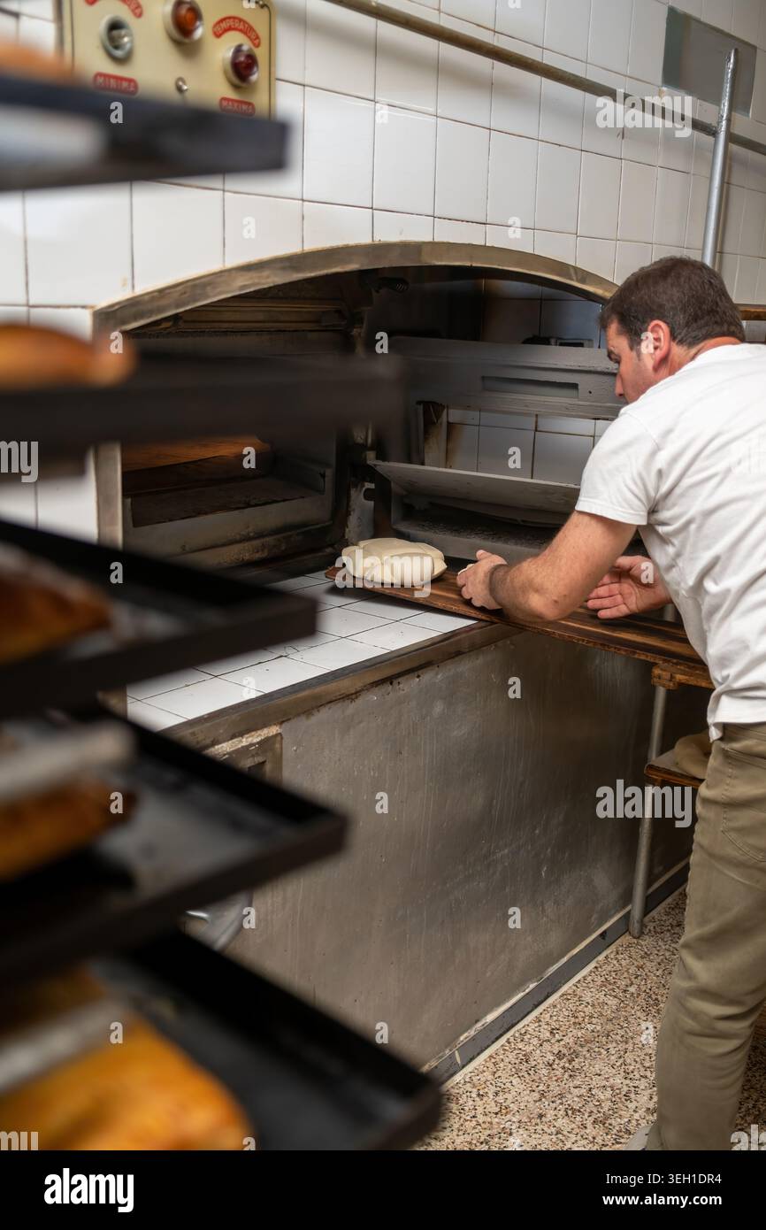 Baker placing fresh bread dough in hot oven Stock Photo